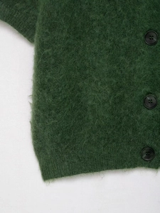 Dettaglio macro della maglia verde scuro con tre bottoni neri lucidi e bordo a costine