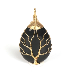 Close-up of handmade tree of life wire wrapping on a teardrop-shaped black stone pendant