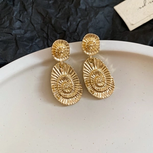 Detailed view of golden spiral swirl earrings with textured metal surface on display