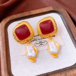 Macro detail of vintage square resin earrings with baroque pearls on a velvet background