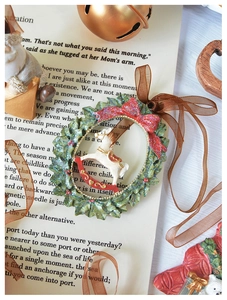 Detail of a vintage Christmas wreath ornament with a white rocking horse and red bow