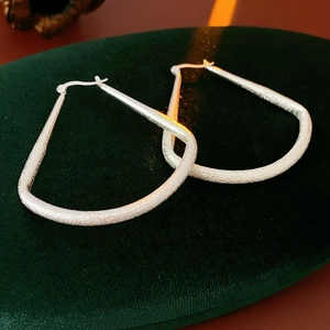 Gros plan de boucles d'oreilles géométriques en argent avec texture sablée mate