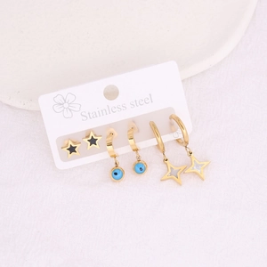 Macro shot of stainless steel earring set with star and evil eye charms in gold finish