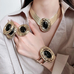 Dettaglio di un set di gioielli vintage dorati con ovali in acrilico nero su modella
