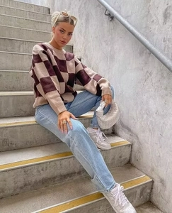 Close-up of oversized brown checkerboard knit sweater styled with blue jeans and sneakers