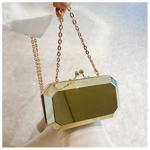 Close-up of gold octagonal acrylic box clutch with mirror finish and chain strap