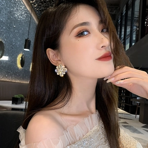 Close-up of sparkling crystal flower earrings worn by a model in elegant indoor lighting