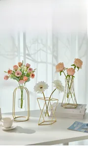 Close-up of geometric gold metal frame vases with glass tubes and artificial flowers