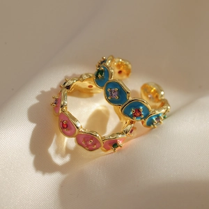 Close-up of golden wavy rings with colorful enamel floral details and small gemstones