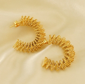 Macro shot of 18K gold-plated C-shaped earrings with intricate wire-wrapped spiral texture