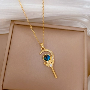 Gold magic wand necklace with angel wings and blue gemstone on white silk