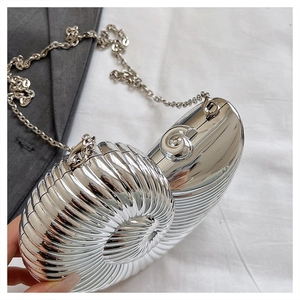 Detailed view of silver snail-shaped evening clutch bag with spiral metallic texture