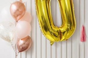 Golden number 0 balloon with rose gold and pink latex balloons in festive party setting