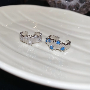 Detail of silver adjustable rings with blue and white zircons on a white plate