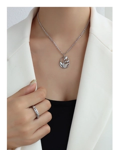 Gros plan du collier pendentif tulipe en argent et de la bague texturée sur mannequin