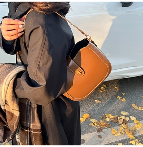 Detail of vintage brown saddle bag with gold square buckle shown from a side view