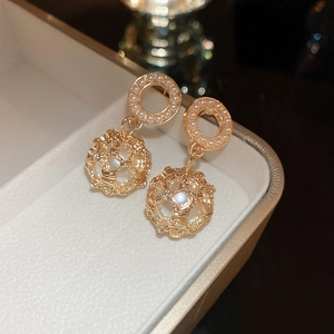 Detail of gold pearl earrings with hollow mesh ball drops and sparkling rhinestones