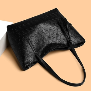 Black tote bag with skull embossed texture and tassel charm on geometric background
