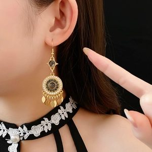 Détail d'une boucle d'oreille dorée vintage avec perles et pompons de feuilles
