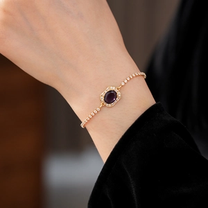 Close-up of a gold-plated bracelet featuring a purple oval stone and white zircon stones