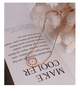 Detail of rose gold snake chain bracelet featuring a blue enamel daisy charm and slide clasp