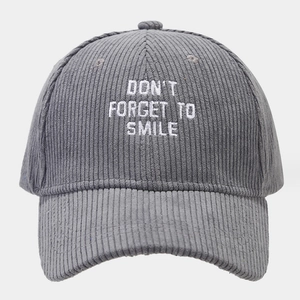 Detailed close-up of white embroidery on gray corduroy baseball cap with text slogan