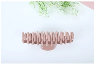 Detail view of large mauve hair claw clip on clean background with floral accent