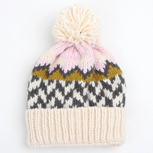 Detail of multi-color geometric knit beanie featuring a fuzzy pom-pom and thick ribbed cuff