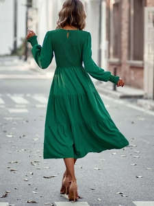Vue arrière d'une robe verte à manches longues avec dos smocké et jupe à plusieurs niveaux