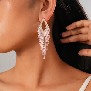 Close-up of pink zircon tassel earrings featuring geometric shapes on model's ear