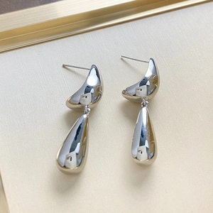 Detail of silver teardrop metal earrings with mirrored polished finish on a tray