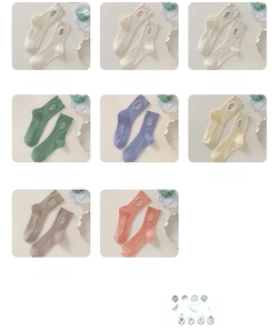 Detail of embroidered tulip socks with ruffled cuffs in eight soft cream pastel colors