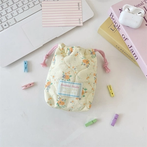 Macro shot of quilted floral drawstring storage bag with soft cotton texture and fabric label