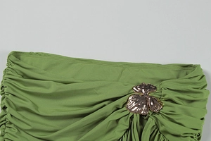 Close-up of olive green pleated fabric with a bronze metal floral decorative buckle
