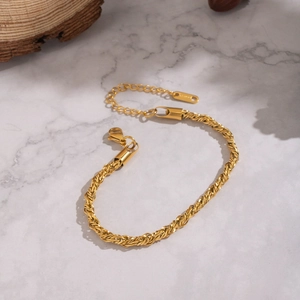 Bracelet élégant à chaîne torsadée en acier inoxydable doré sur fond de marbre
