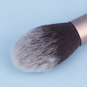 Macro detail of flame-shaped makeup brush with soft gradient bristles and rose gold ferrule