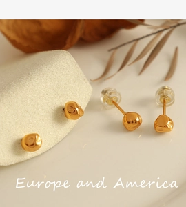 Macro shot of minimalist gold bean stud earrings with irregular crushed metal texture