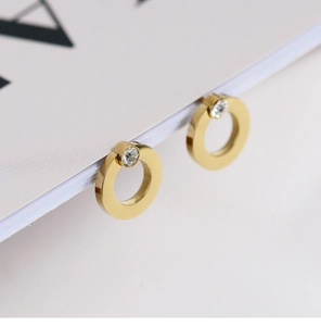 Close-up of geometric gold hoop earrings with small sparkling zircon stones in 18K plating
