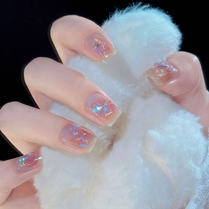Detail of pink press-on nails with iridescent glitter and 3D bow charms on square tips