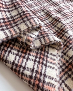 Close-up of thick plaid cashmere-like scarf showing soft texture and tassel details