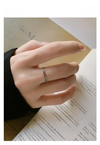 Detail of S925 silver heart ring with colorful zircons worn over a vintage book page