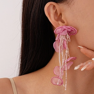Macro view of long pink organza flower earrings with beaded tassels on model