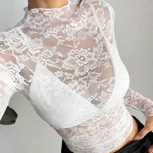 Detail of white long sleeve lace top featuring high neck and floral hollow-out pattern