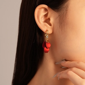 Close-up of matte red petal earrings with gold hoop and sparkling rhinestone detail