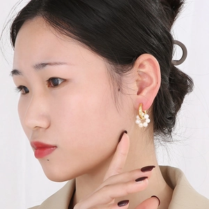 Close-up of model wearing retro gold hollow hoop earrings with elegant white pearl details