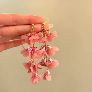 Detailed macro view of pink lily of the valley tassel earrings held by hand for vacation style