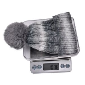 Detailed view of grey gradient knit beanie with faux fur pom pom weighing 107.8 grams
