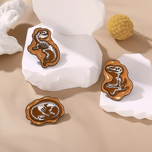 Set of 3 dinosaur fossil skeleton enamel pins on a warm sand background aesthetic