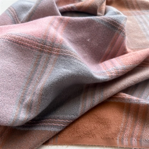 Close-up of pink and grey plaid scarf showing soft brushed cashmere texture and tassels