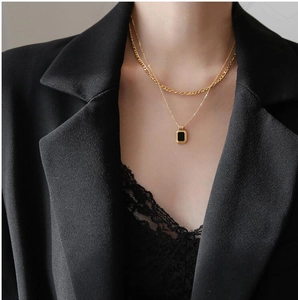 Double-layered gold necklace with black square pendant on professional office attire